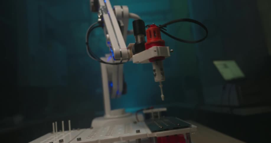 A detailed close up shows a small advanced robotic arm operating with precision in a dimly lit futuristic laboratory