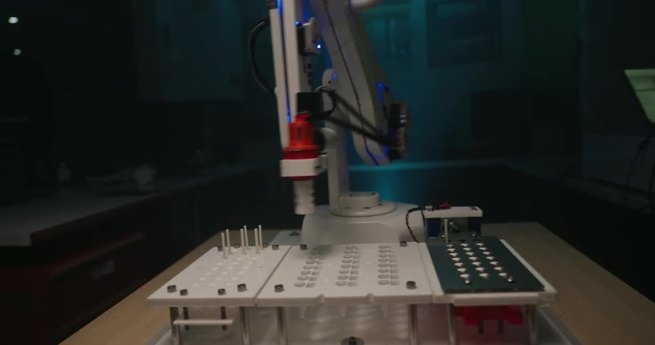 A specialized robotic arm performs precise automated work moving its needle like head over a grid of small components