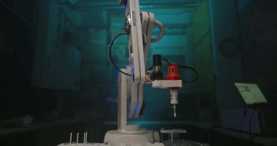 The robotic arm moves and inserts a plastic needle into a hole