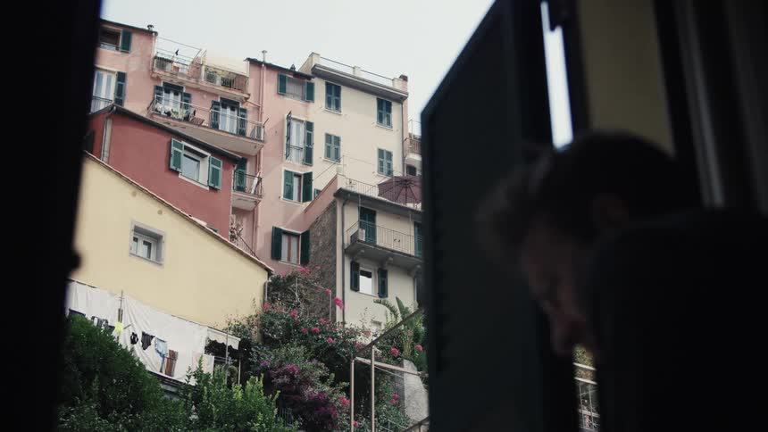 Colorful houses with clotheslines and flowers are seen through an open window