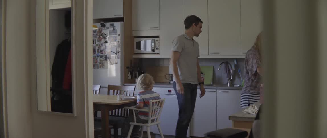 Man looks at toddler and takes plate out of kitchen cupboard