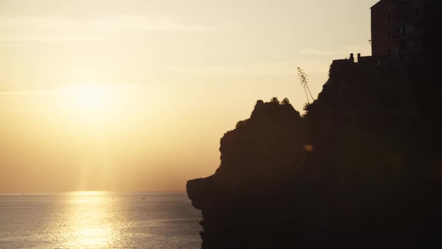 The sun is rising over the ocean by the cliff