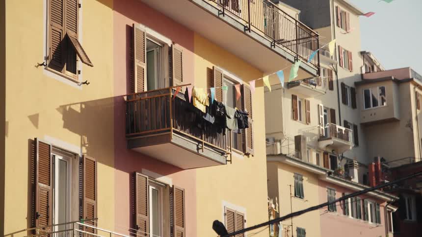 A multistory yellow building with balconies stands under the bright midday sun