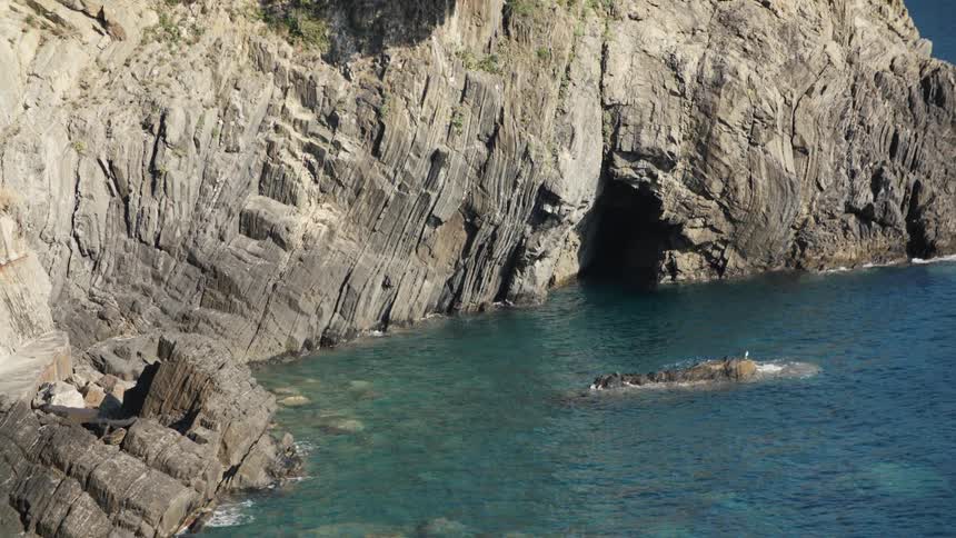 A dark cave is on the shore in the mountain