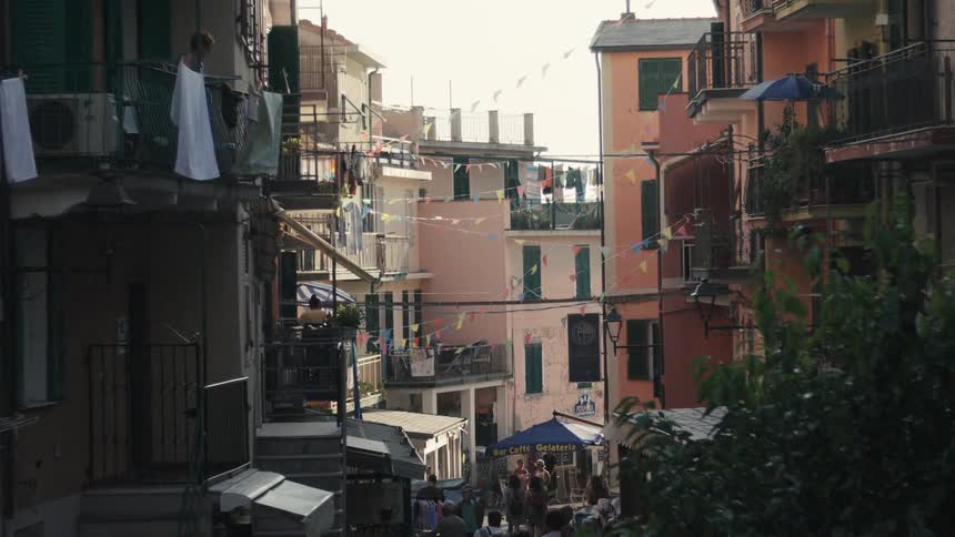 Narrow street lined with colorful buildings featuring balconies and decorative pennants