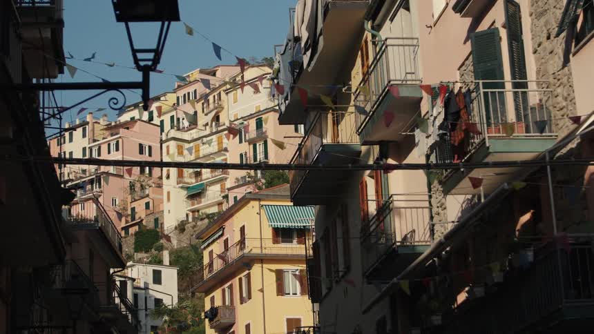 Hillside houses with colorful facades clotheslines on balconies and flags strung across the street