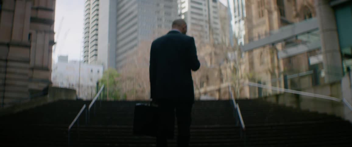 The man stands in front of steps in the big city