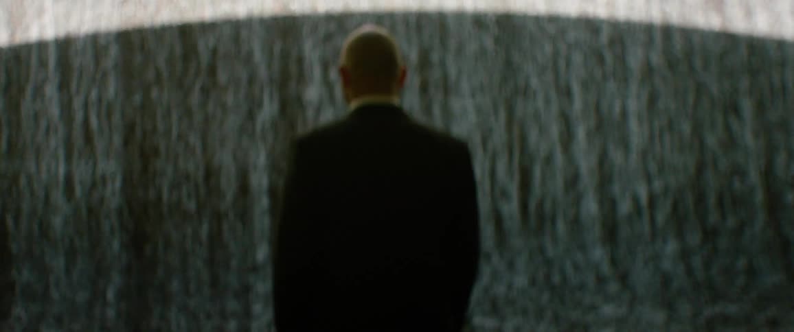 Person in a suit seen from behind standing before a flowing water wall
