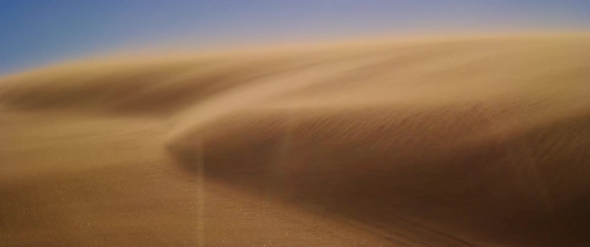 Sand dune shaped by the wind under a clear blue sky