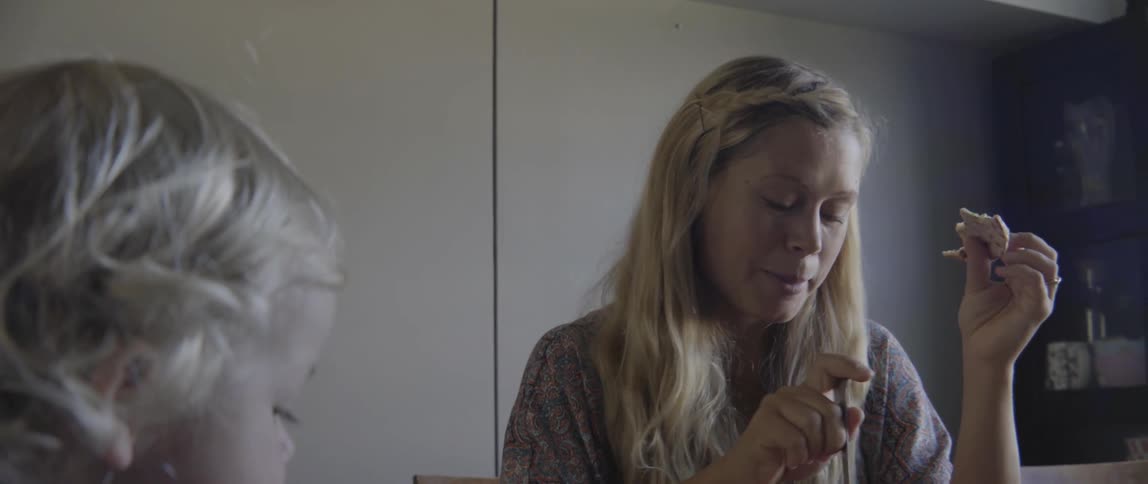 A woman shares a conversation with a young toddler boy while eating dinner.