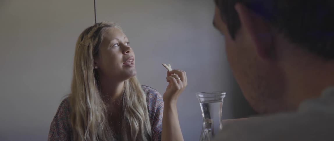 A happy young family shares a meal and talks together at a kitchen table.