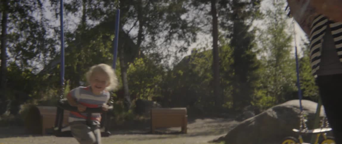 Young woman and toddler boy enjoying a playful sunny afternoon on the swings.