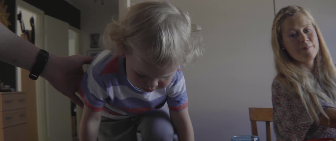 An energetic toddler boy runs toward his high chair for a fresh family meal.