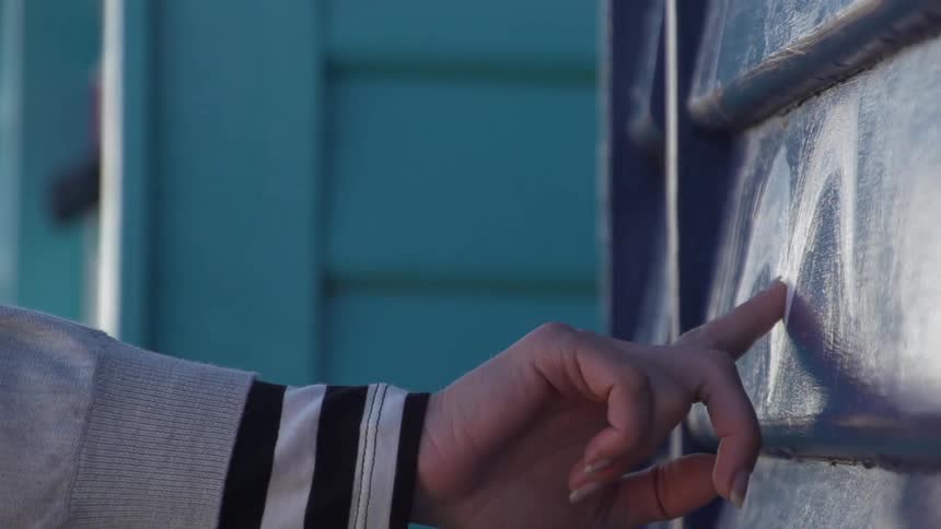 A woman tracing a letter on a wall with her fingertip