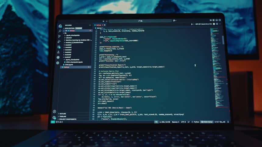 A programming code is displays on a laptop screen in a dimly lit setting