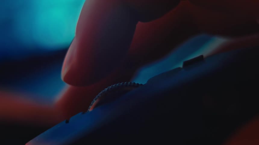 Closeup of a hand scrolling a computer mouse under blue and red lighting