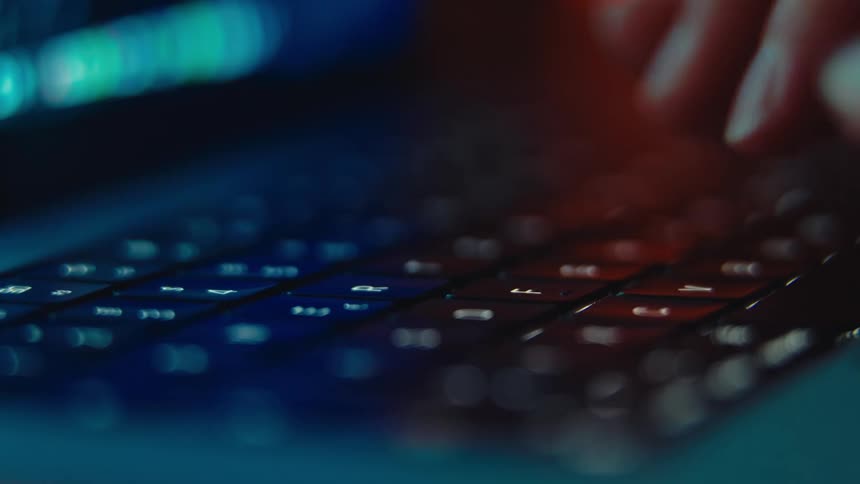 Extreme close up of a person typing while coding on a laptop computer in a room