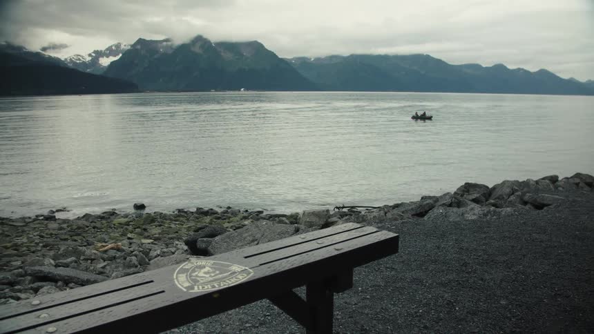 The row boat travels in the lake by the mountains