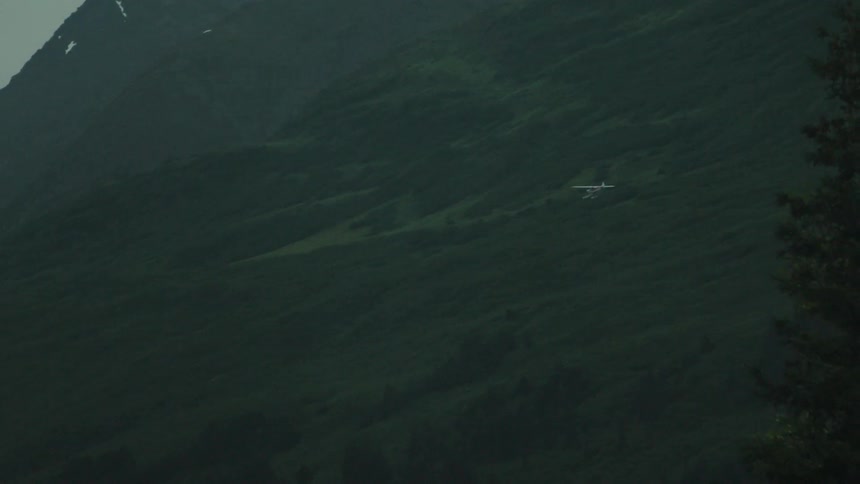 A small airplane gliding in the sky while a bus passes by on the ground