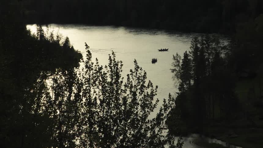 Silhouette of a group of people on two boats on a lake outdoors
