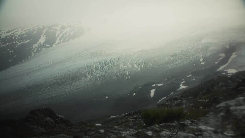Dense haze partially obscures a snow dappled mountain slope on a winter day