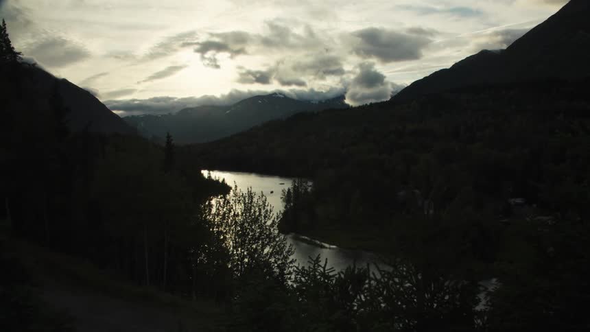 River surrounded by mountains in cloudy weather outdoors during dusk or dawn