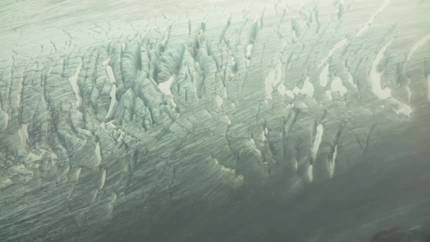 Glacier surface marked by deep crevasses and irregular ice patterns