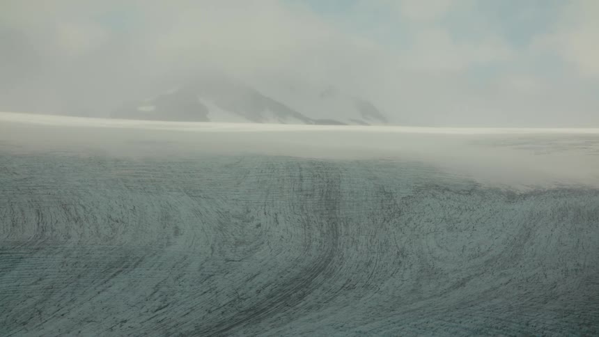 Fog and low lying clouds partially cover a snowy mountain landscape