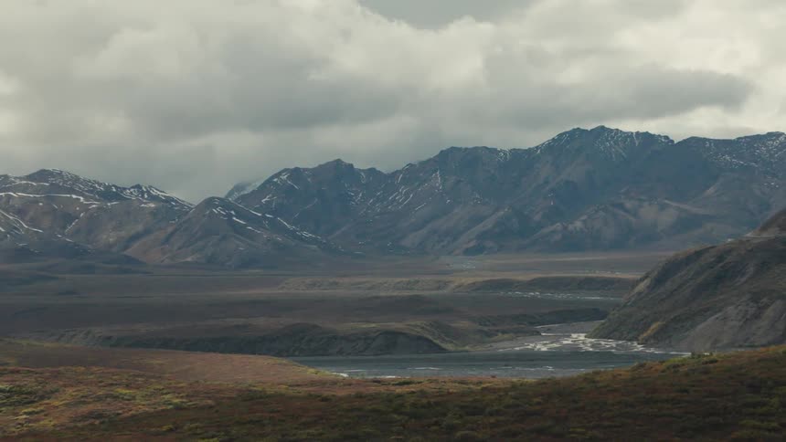 Mountain landscape with river and colorful vegetation under cloudy sky