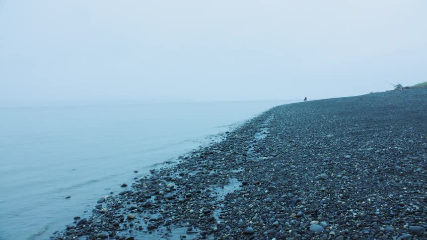 Pebble beach on a cloudy morning with calm sea in the background