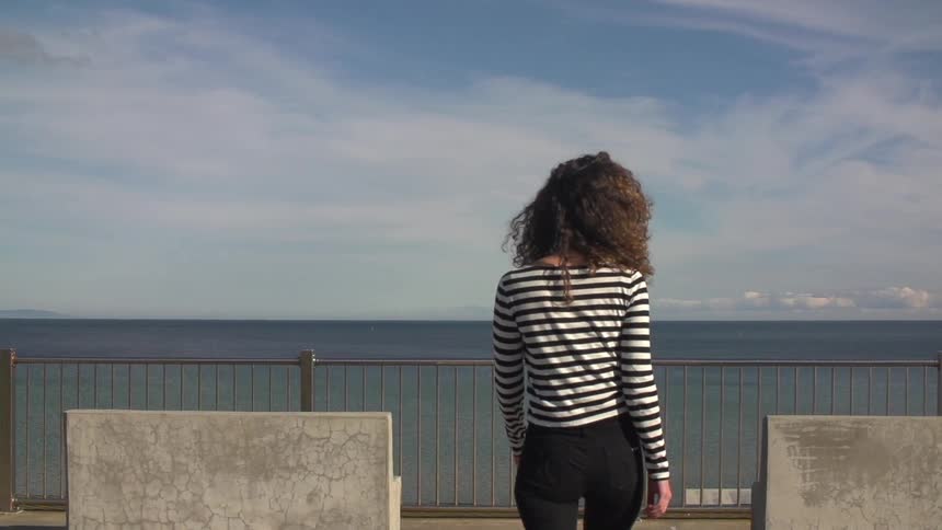 Woman walking over to a railing by water