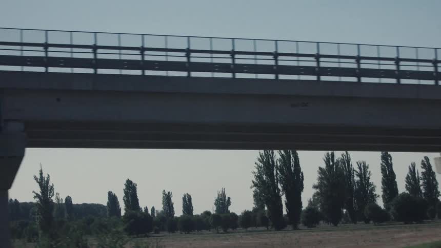 Concrete bridge spans an area with vegetation under a clear sky
