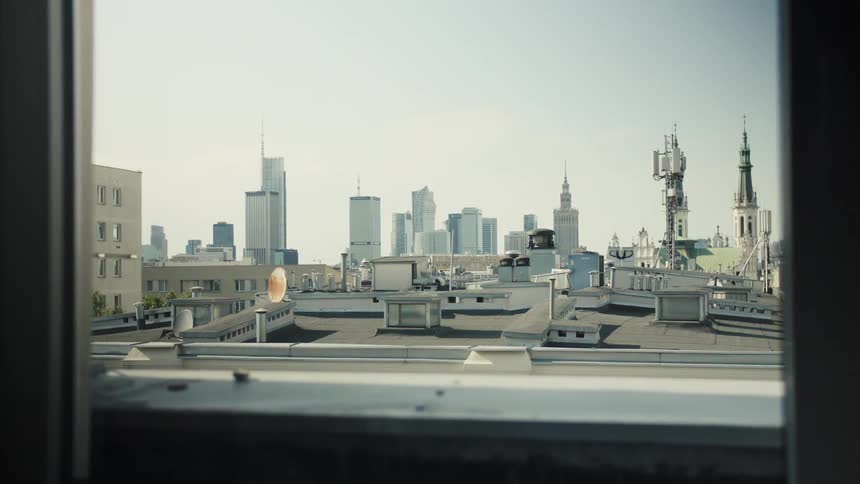 A high rise building rooftop through a window in a metropolitan city during daytime