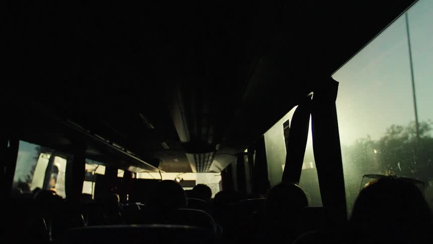 Silhouettes of a group of people on a road trip in a long bus during daytime