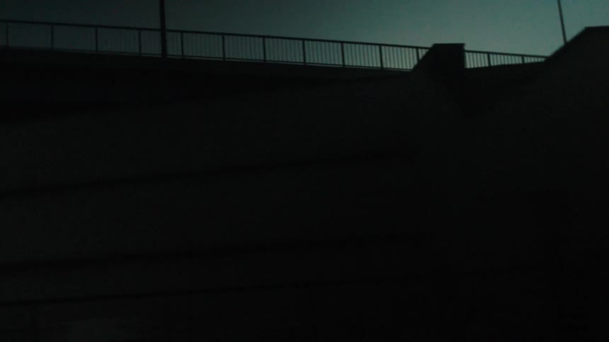 Car crosses a bridge at dusk under a dark blue sky