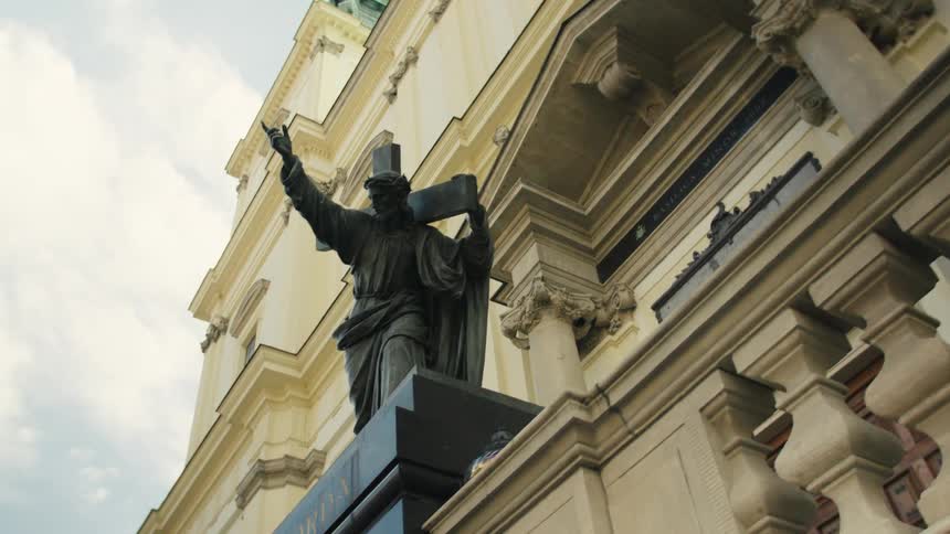 Statue with a raised cross on the balcony of a historic building