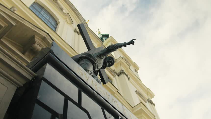 The sculpture of christ bearing his cross stands before the holy cross church in warsaw poland under a cloudy sky