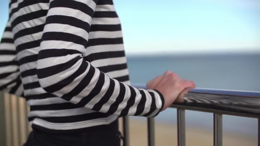 Woman leans against a railing outside