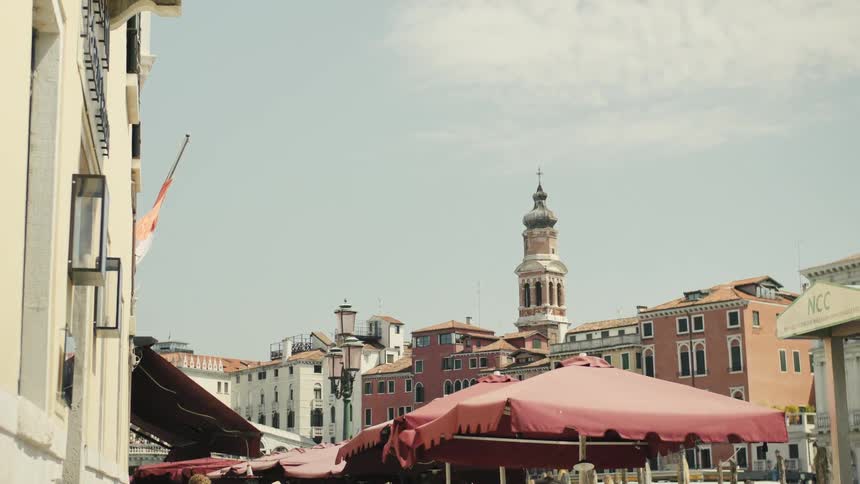 Church tower stands out among historic buildings and red canopies under the sun