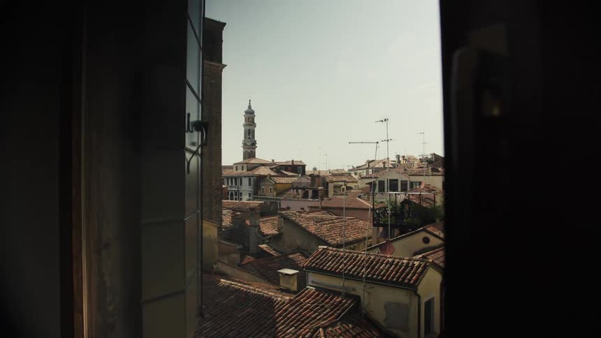 View of rooftops and a distant tower through an open window