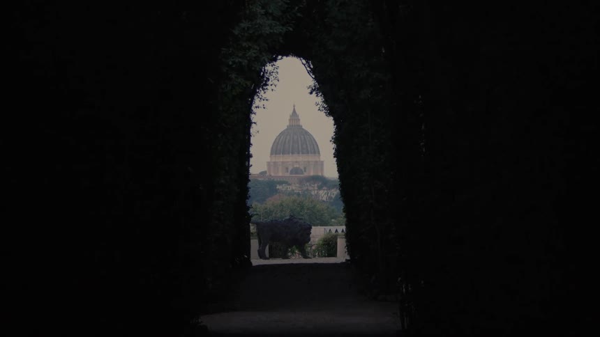 Monumental dome appears in the distance framed by a tunnel of dark foliage