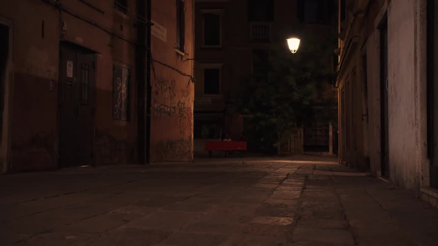 The person walks past the alley at night