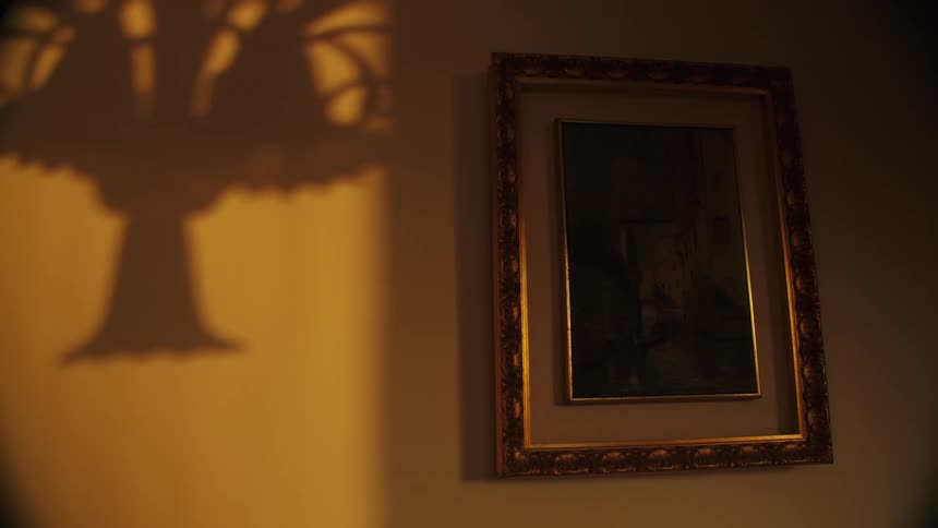Light fixture casts a shadow on the wall next to a painting with a gilt frame