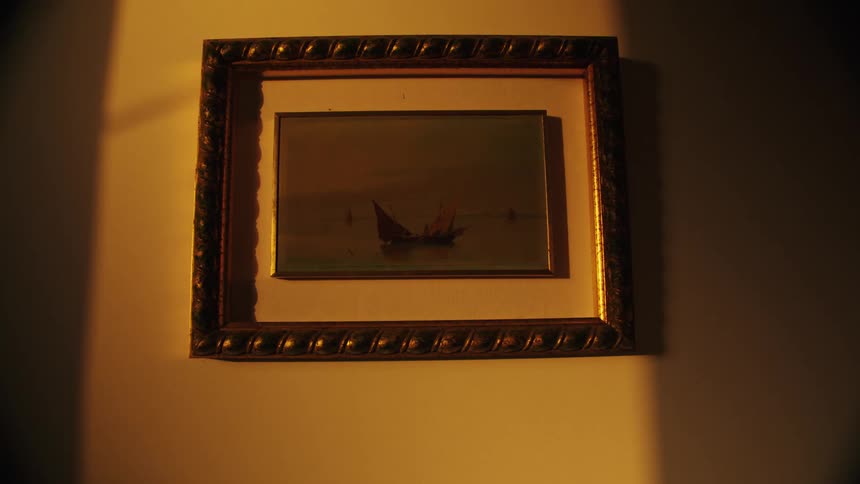 Framed painting of boats illuminated by the golden light of sunset