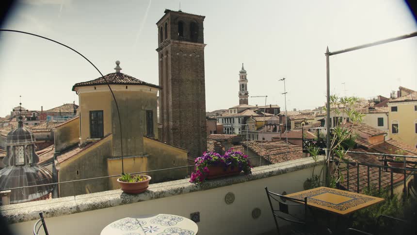 Terrace with decorated tables and flowers offers a view of historic rooftops and towers of an old city