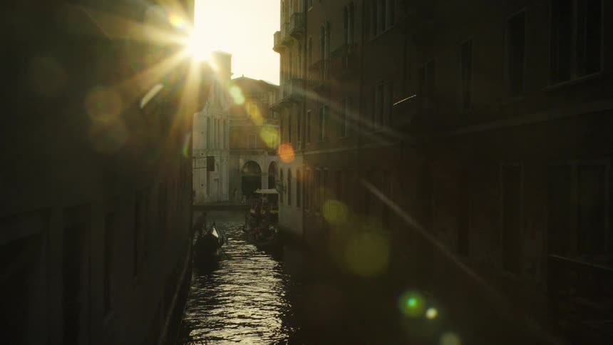 A cityscape glows at sunset with a canal winding through its center reflecting the warm hues of the fading sun