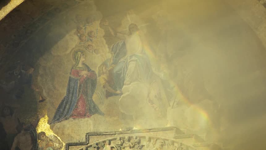 Religious fresco illuminated by a beam of light reveals celestial figures among clouds