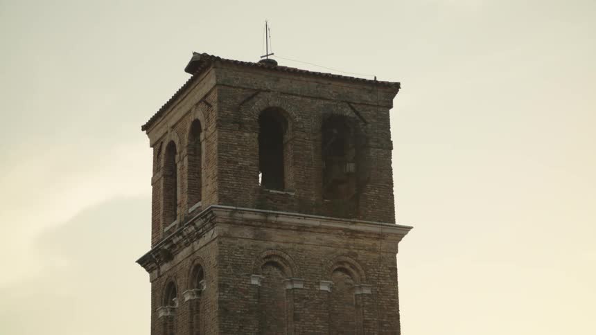 Brick tower with arched windows stands out under a clear sky at sunset