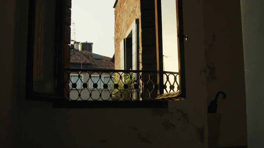 Open window reveals old buildings bathed in the soft light of sunset
