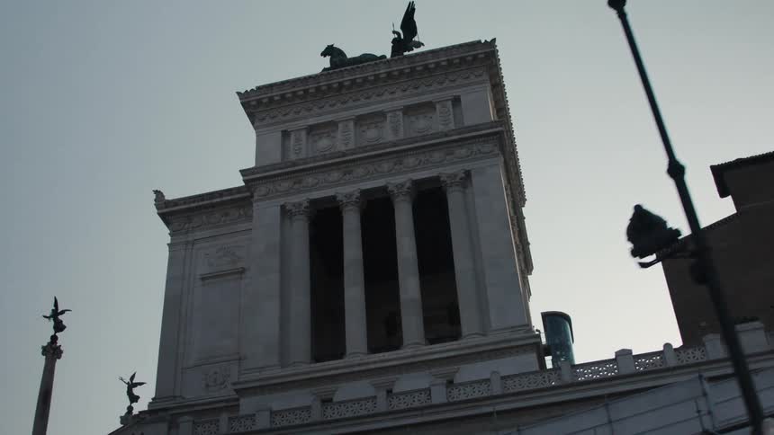 Monumental building with columns and a horse sculpture on top against the clear sky